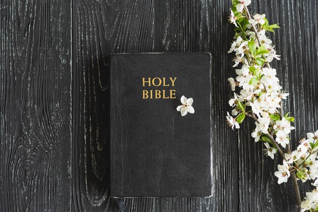 The bible with spring flowers on a wooden background concept for faith