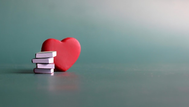 Photo bibliophile book lover concept stack of books and red heart with copy space for text