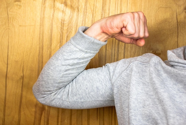 Biceps op de arm Atleet in hoodieMuscles of the hand Sportman in sweatshirt Show armspieren in sweater