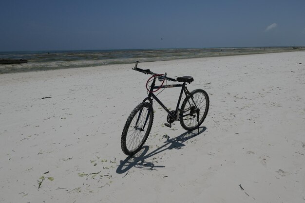 Foto bicicletta sulla spiaggia contro un cielo limpido