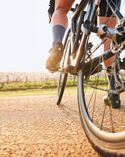 Bicycle closeup countryside ride and person on a bike with speed for sports race on a gravel road Fitness exercise and athlete legs doing sport training in nature on a trail for cardio and workout