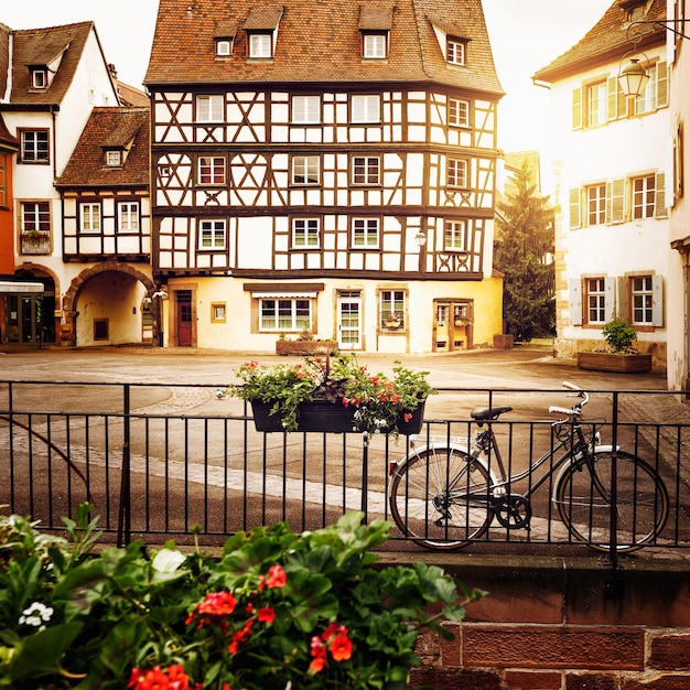 Bicycle on cobblestone street with half timbered houses in\
colmar alsace france toned in warm colors