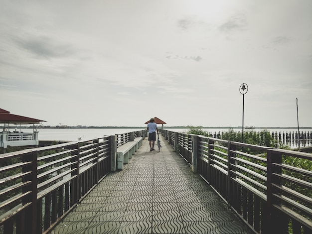 Photo bicycle cycling and men on the big bridge which leads to the vast sea