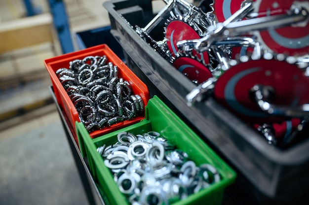 Bicycle factory, boxes with bike parts, closeup view, nobody. Baskets with cycle connecting rods and bearing, assembly line in workshop