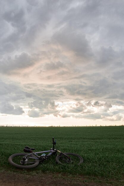 Bicycle on a field against dramatic evening sky during early spring