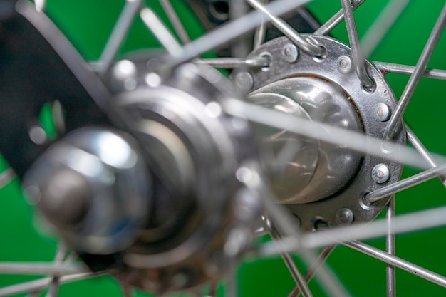 自転車のフロントホイールハブにスポークが付いている緑色の背景の詳細