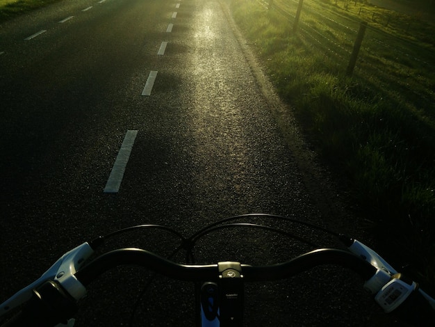 Bicycle handlebar on road during sunset