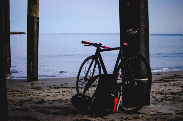 Photo bicycle leaning on pole at beach