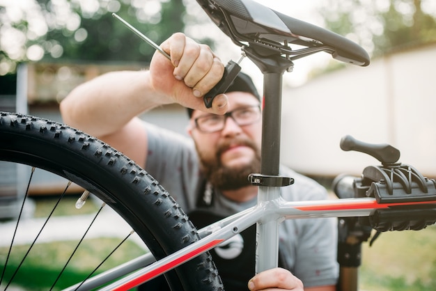 自転車整備士は、サービスツールの自転車サドルで調整します。