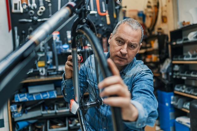 Bicycle mechanic carrying a bike in workshop