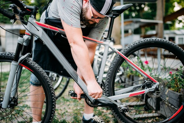 Le mani del meccanico della bicicletta regolano i pedali del ciclismo