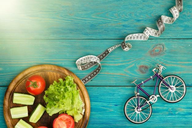 Bicycle model fresh vegetables and centimeter tape on blue wooden desk