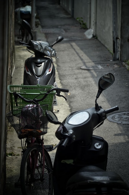 Photo bicycle and motor scooters parked on footpath amidst buildings