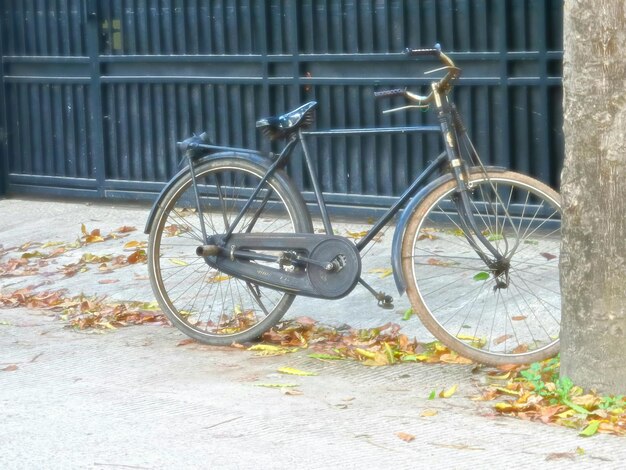 Photo bicycle parked against metallic fence