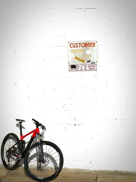 Bicycle parked against white wall with placard sign