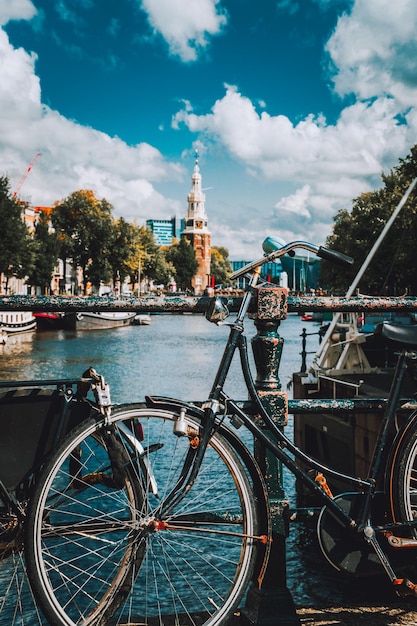 Foto bicicletta parcheggiata sul ponte sul fiume contro il cielo nuvoloso in città