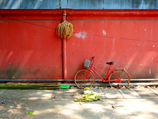 Bicycle parked on sidewalk against wall