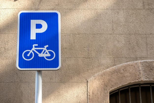 Bicycle parking sign on a sunny day in europe agains stone wall with copy space