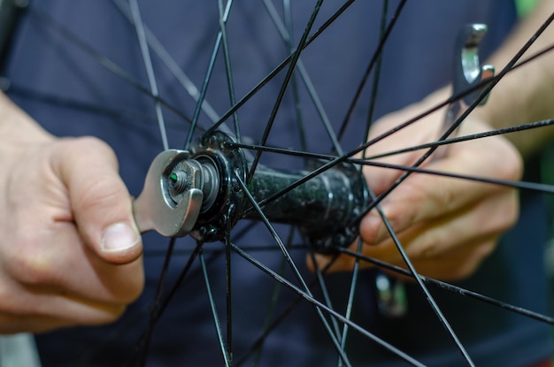 自転車の修理自転車のハブベアリングの潤滑とクリーニングの交換マスタープロのキーの手で勤勉な手のクローズアップ