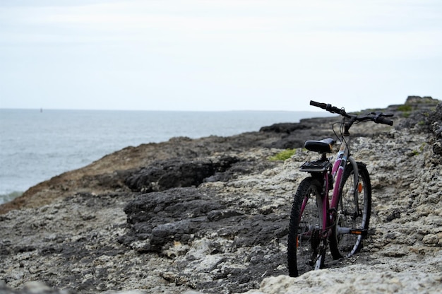 Photo bicycle on rock by sea against sky