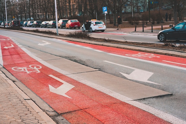 Знак велосипеда нарисовал на поверхности дороги красная велосипедная дорожка в городе. часть проезжей части предназначена только для велосипедистов. указатели поворота. безопасность. безопасность. велосипедная дорожка. асфальтированная дорога