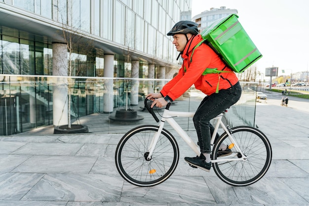 写真 ヘルメットをかぶった宅配業者の男性に自転車で注文し、サーモバッグに入れて顧客の住所に食品を配達する