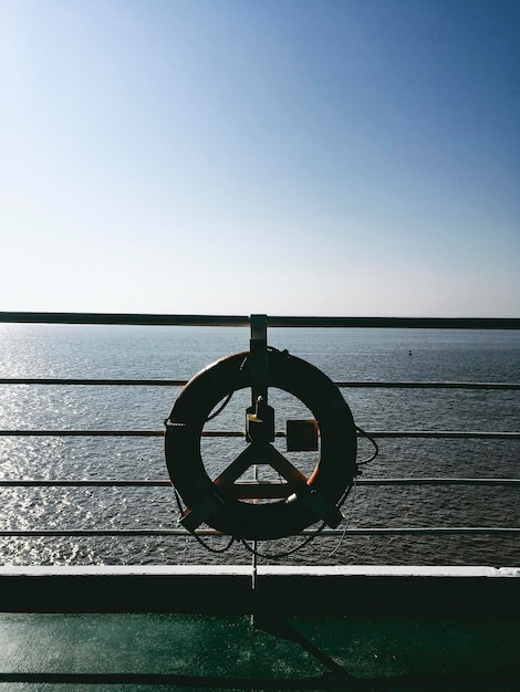 Bicycle wheel by sea against clear sky