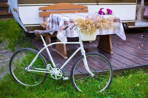 A bicycle with a basket on it sits on a lawn next to a table with a table