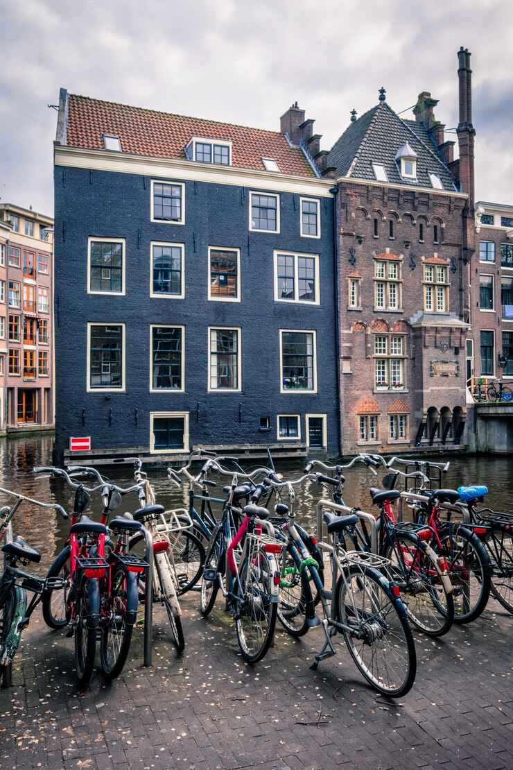 Photo bicycles in amsterdam street near canal with old houses