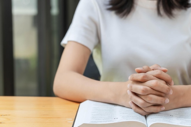 Bid en religie concept Vrouwelijke christelijke handen gevouwen en bijbel lezen om te bidden voor spiritualiteit