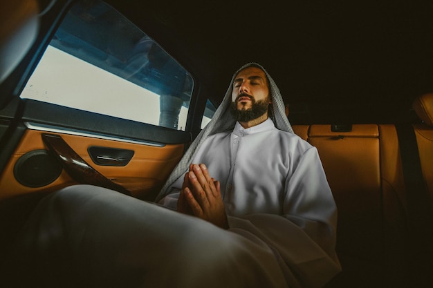 Bidden in een auto Een jonge rijke saudi in een leren auto-interieur bidden