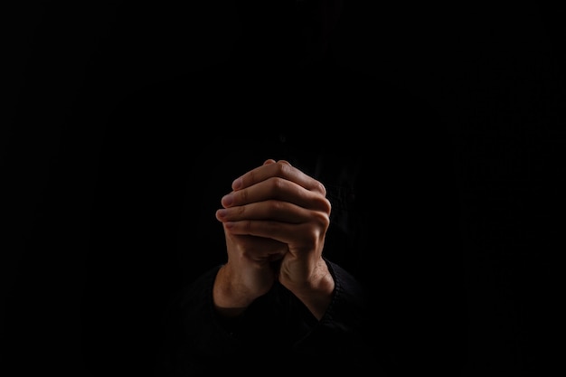 Foto biddende handen op zwarte achtergrond