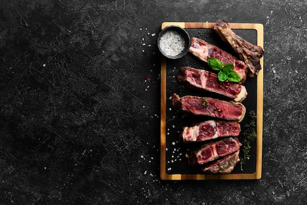 Biefstuk met bot op het keukenbord Tomahawk steak op een zwarte houten ondergrond Bovenaanzicht Vrije ruimte om te kopiëren