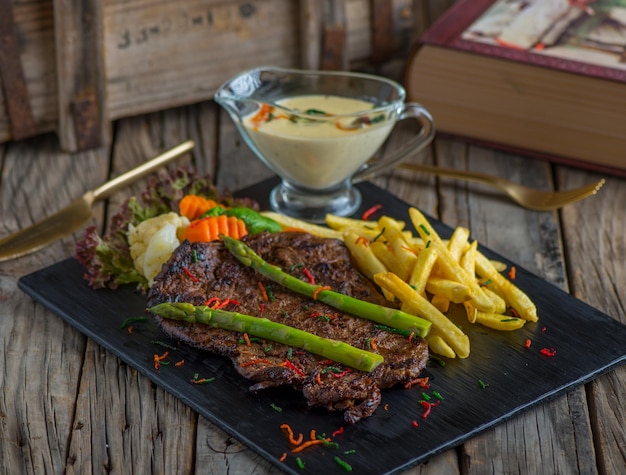 Biefstuk met frietjes geïsoleerd op snijplank op houten achtergrond zijaanzicht van steak