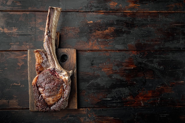 Biefstuk op het bot. tomahawk steak vers gegrilde droge leeftijd BBQ-voedsel set, op houten serveerplank, op oude donkere houten tafel achtergrond, bovenaanzicht plat lag, met kopie ruimte voor tekst