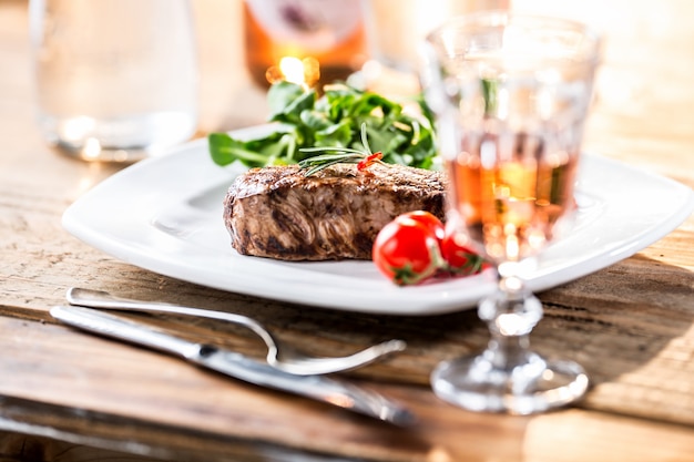 Biefstuk. Sappige biefstuk. Gastronomische steak met groenten en glas rose wijn op houten tafel.