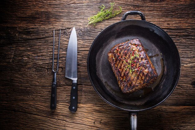 Biefstuk. Sappige Rib Eye steak in pan op houten bord met vork en mes.