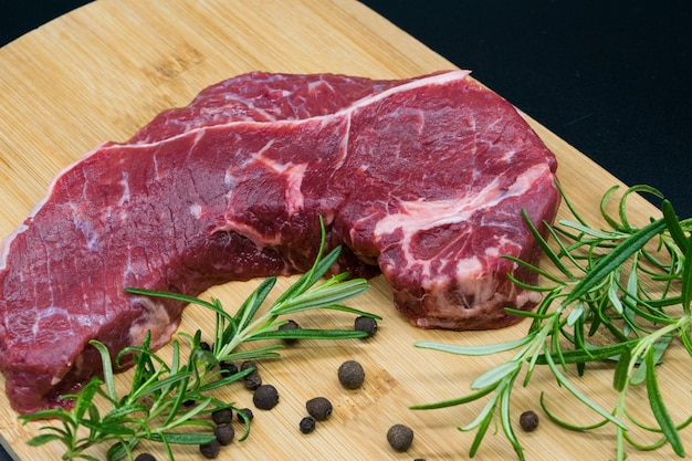 Biefstuk weergave van vers rundvlees op een houten bord met rozemarijn zwarte peper toilet blad