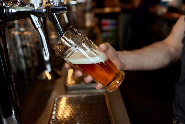 Bier gieten in een mok in een bierbar close-up bier bottelen in het restaurant de toog