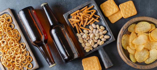 Bier in glazen flessen en zoute snacks voor bier. Grijze concrete achtergrond. Het concept van een feest voor vrienden.