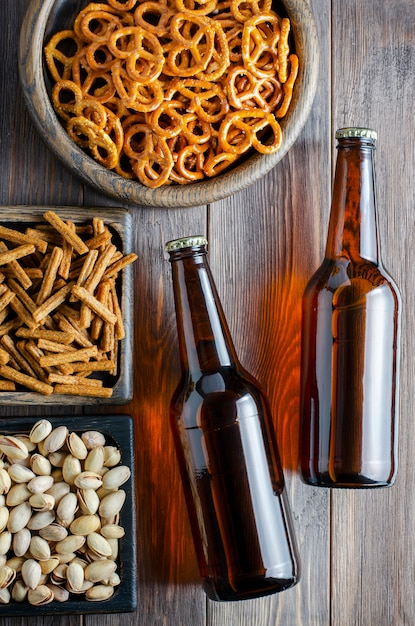 Bier in glazen flessen en zoute snacks voor bier in houten gerechten