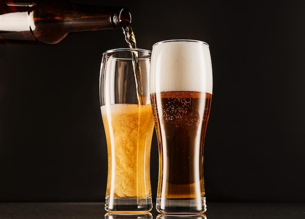 Bier in glazen uit fles gieten op donker