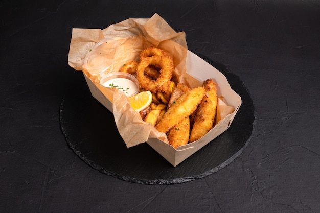 Bier snacks inktvis ringen kaas sticks frietjes op een zwarte achtergrond zijaanzicht