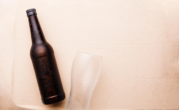 Bierfles en glas op een zandstrand