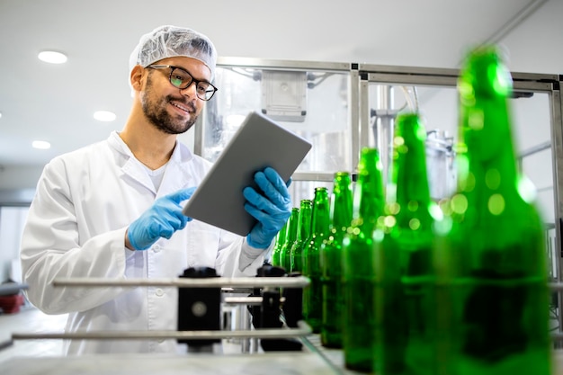 bierflessen in beweging en technoloog die de productie van alcoholische dranken in de bottelarij controleert;