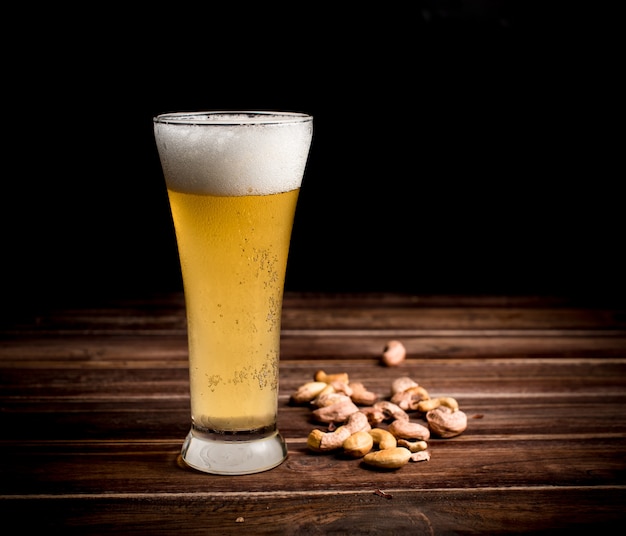 Foto bierglas en cashewnoot op houten lijst, donkere achtergrond