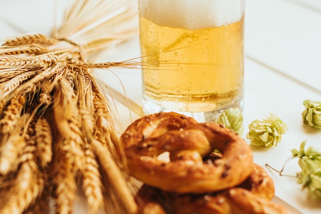 Bierpul, hopbellen en pretzels op een witte houten tafel.