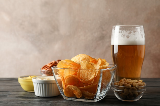 Biersnacks, glas bier, chips, biernoten, sauzen, glas bier op houten, ruimte voor tekst