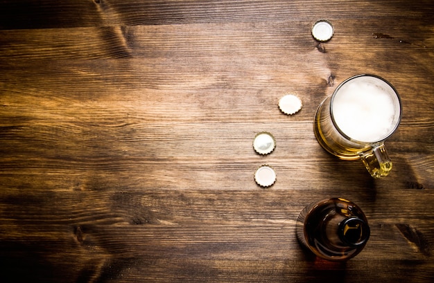 Bierstijl - fles, bier in het glas en covers op houten tafel