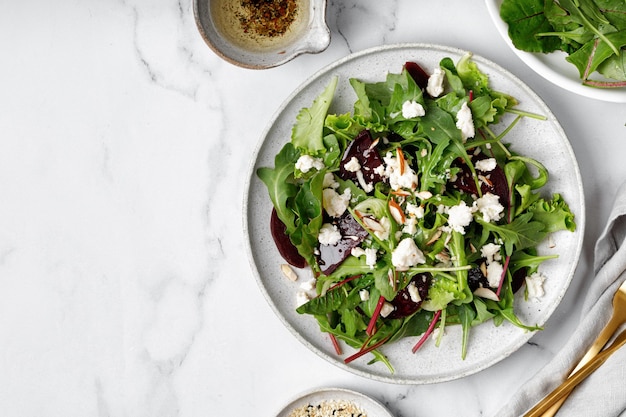 Bieten- of bietensalade met groene mix sla noten feta kaas op wit bord met vorkolie